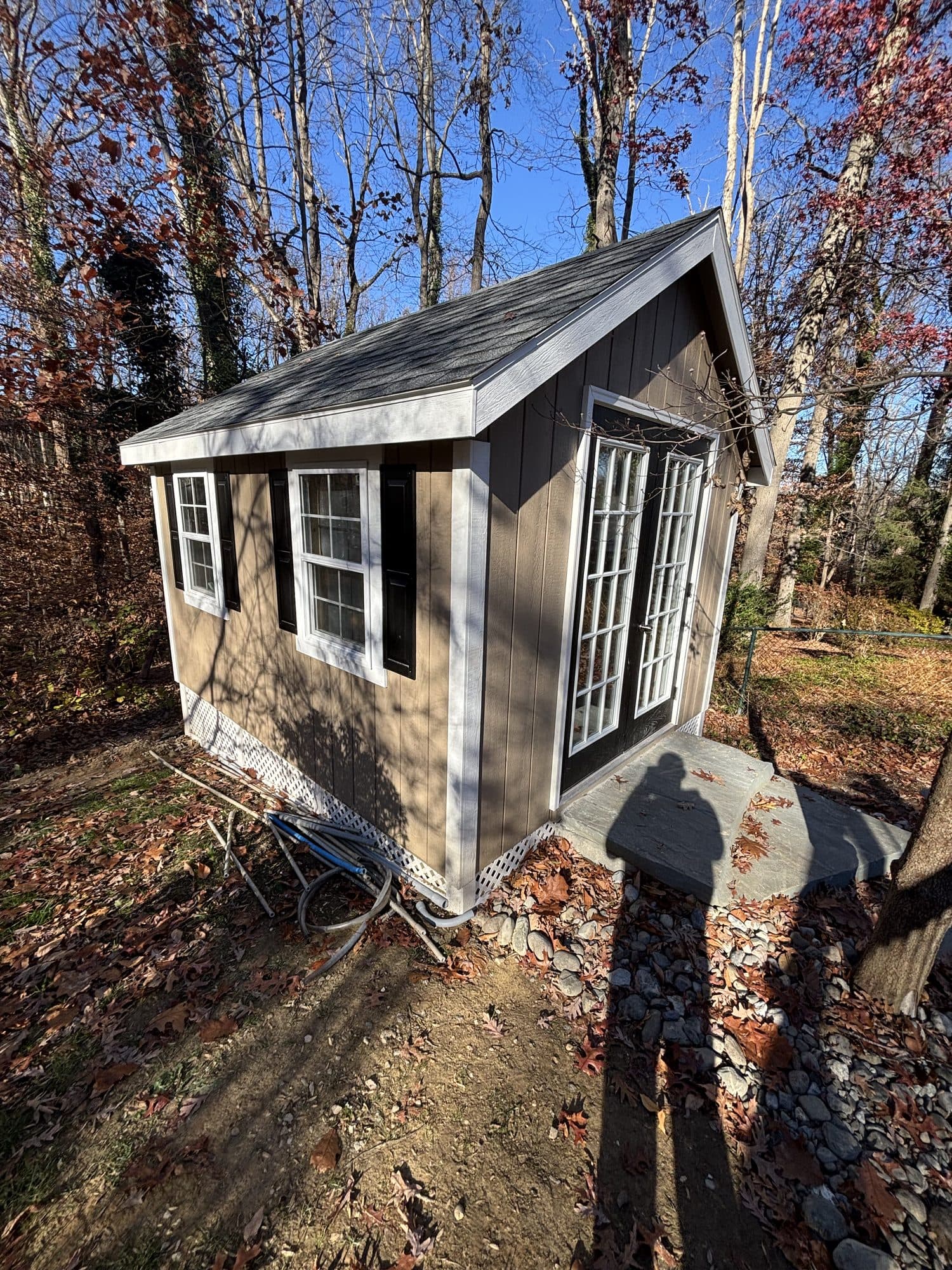 Completed room addition with brown board-and-batten siding, black-trimmed windows, and french doors among trees. Home addition project by Potts Brothers Construction, Arlington & Northern Virginia