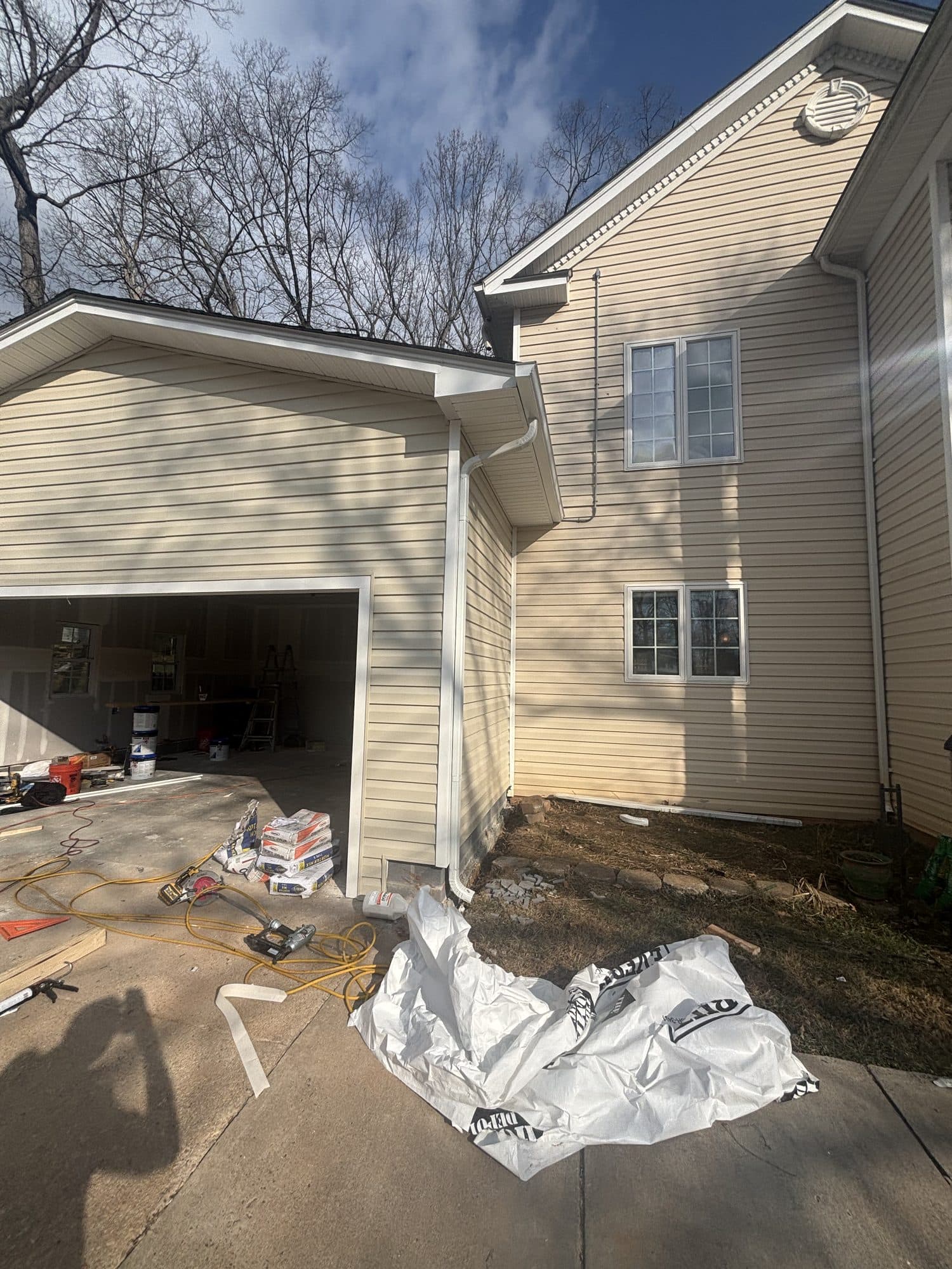 A two-story home with new cream lap siding, seamless gutters, and an attached garage. Home addition project by Potts Brothers Construction, Arlington & Northern Virginia