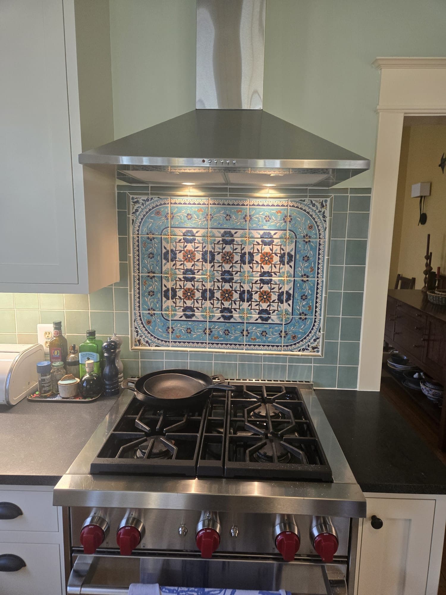 A remodeled kitchen range wall with a stainless hood and an ornate blue-and-white decorative tile backsplash. Home addition project by Potts Brothers Construction, Arlington & Northern Virginia