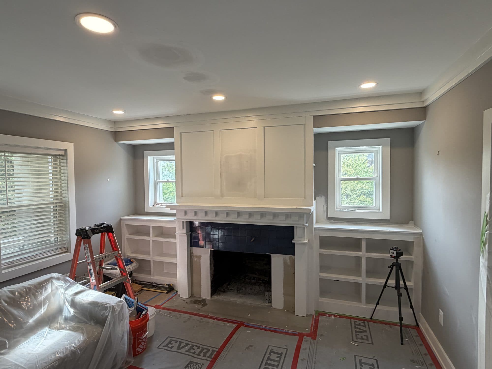A living room with custom built-in bookcases flanking a paneled fireplace surround, freshly finished. Home addition project by Potts Brothers Construction, Arlington & Northern Virginia