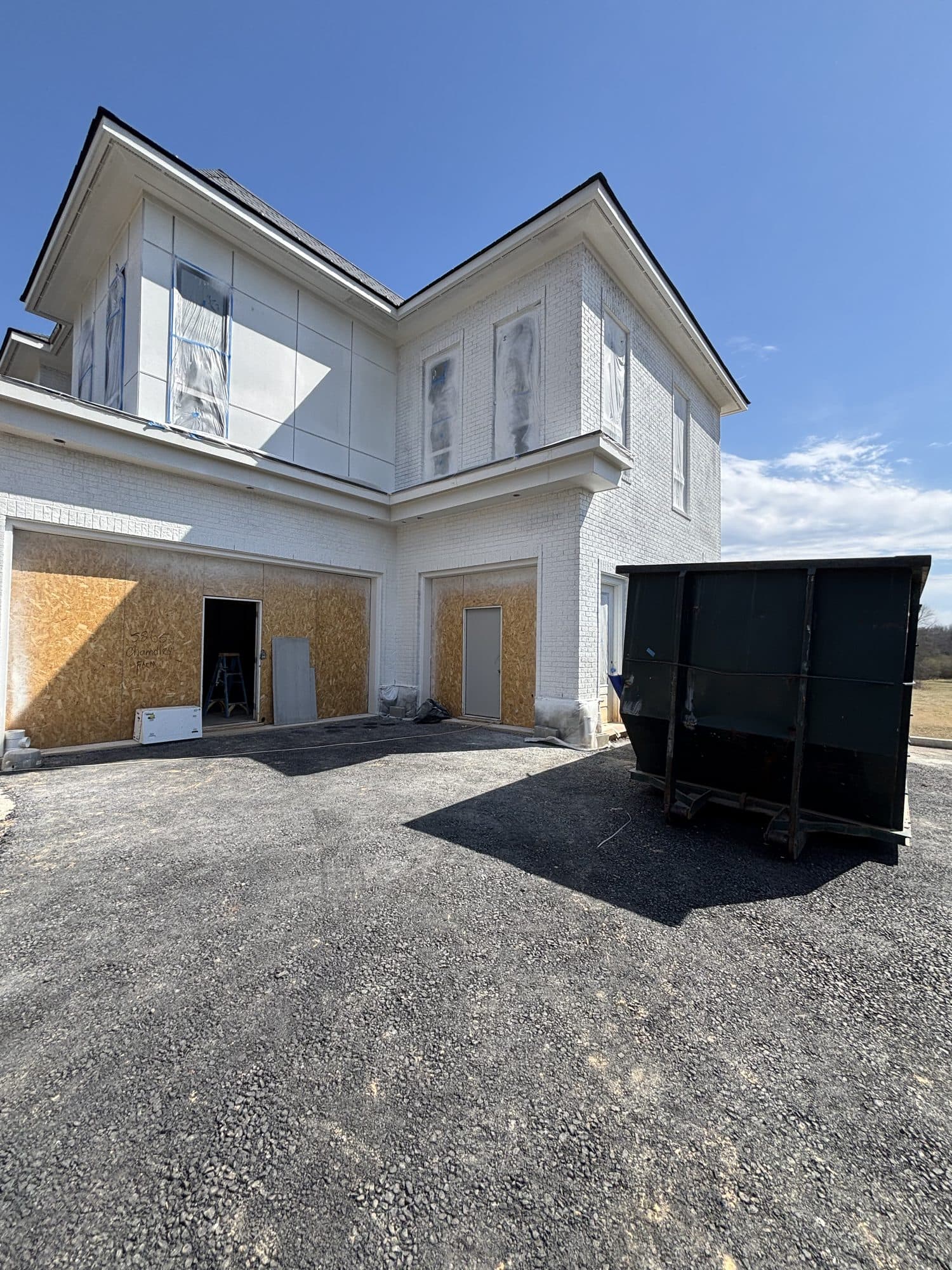 A whole-home remodel nears completion with fresh white stucco beside a dumpster on site. Home addition project by Potts Brothers Construction, Arlington & Northern Virginia