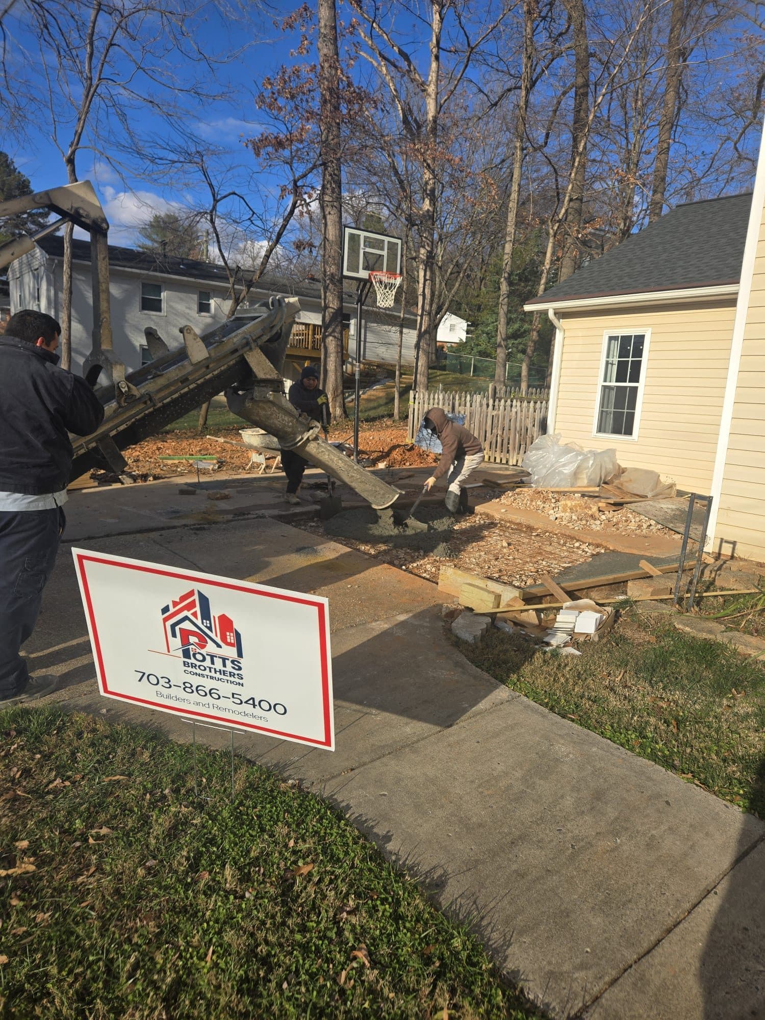 Concrete crew finishing a freshly poured backyard pad on a sunny day. Concrete project by Potts Brothers Construction, Arlington & Northern Virginia