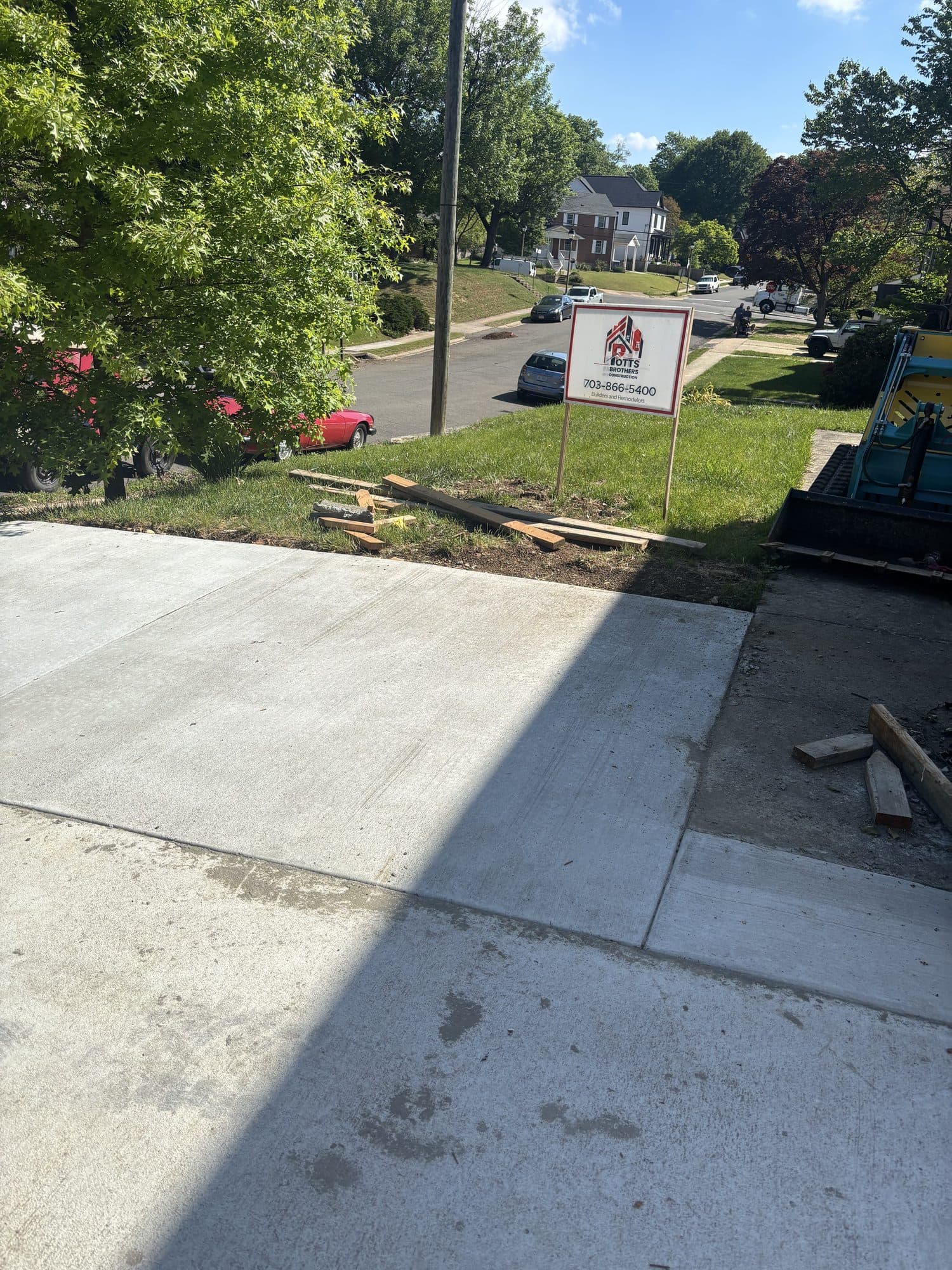A freshly poured and finished concrete driveway running from the street, with clean control joints and a fresh curb apron. Concrete project by Potts Brothers Construction, Arlington & Northern Virginia
