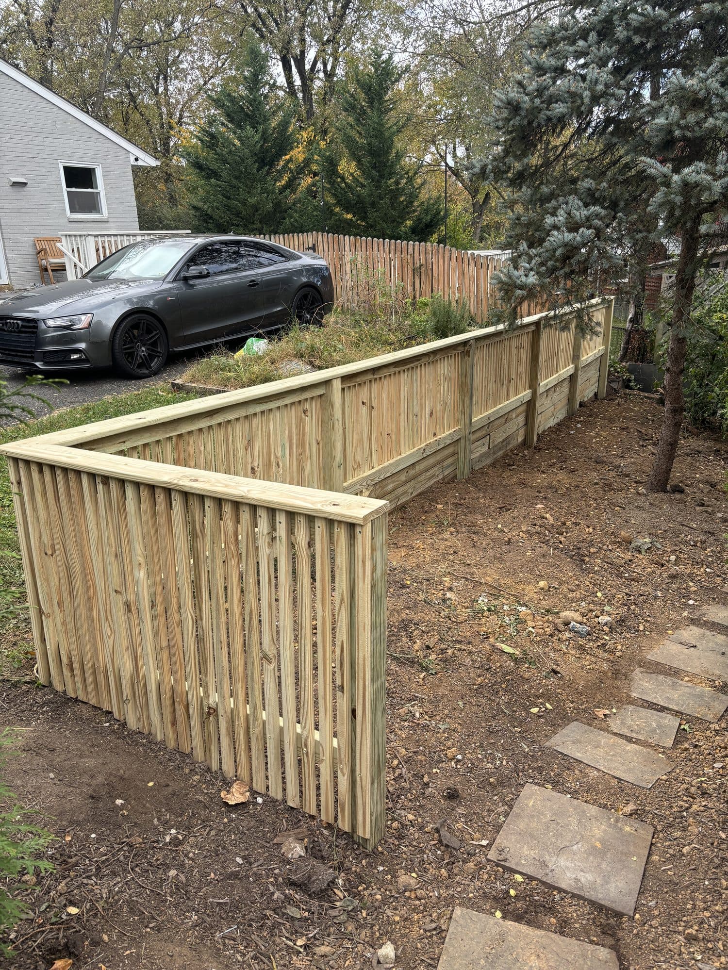 New wood retaining wall along sloped yard. Concrete project by Potts Brothers Construction, Arlington & Northern Virginia