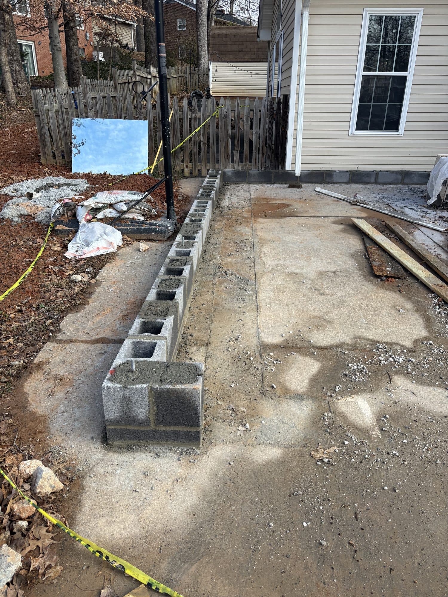A low concrete block foundation wall built along the edge of a concrete patio beside a home. Foundation project by Potts Brothers Construction, Arlington & Northern Virginia