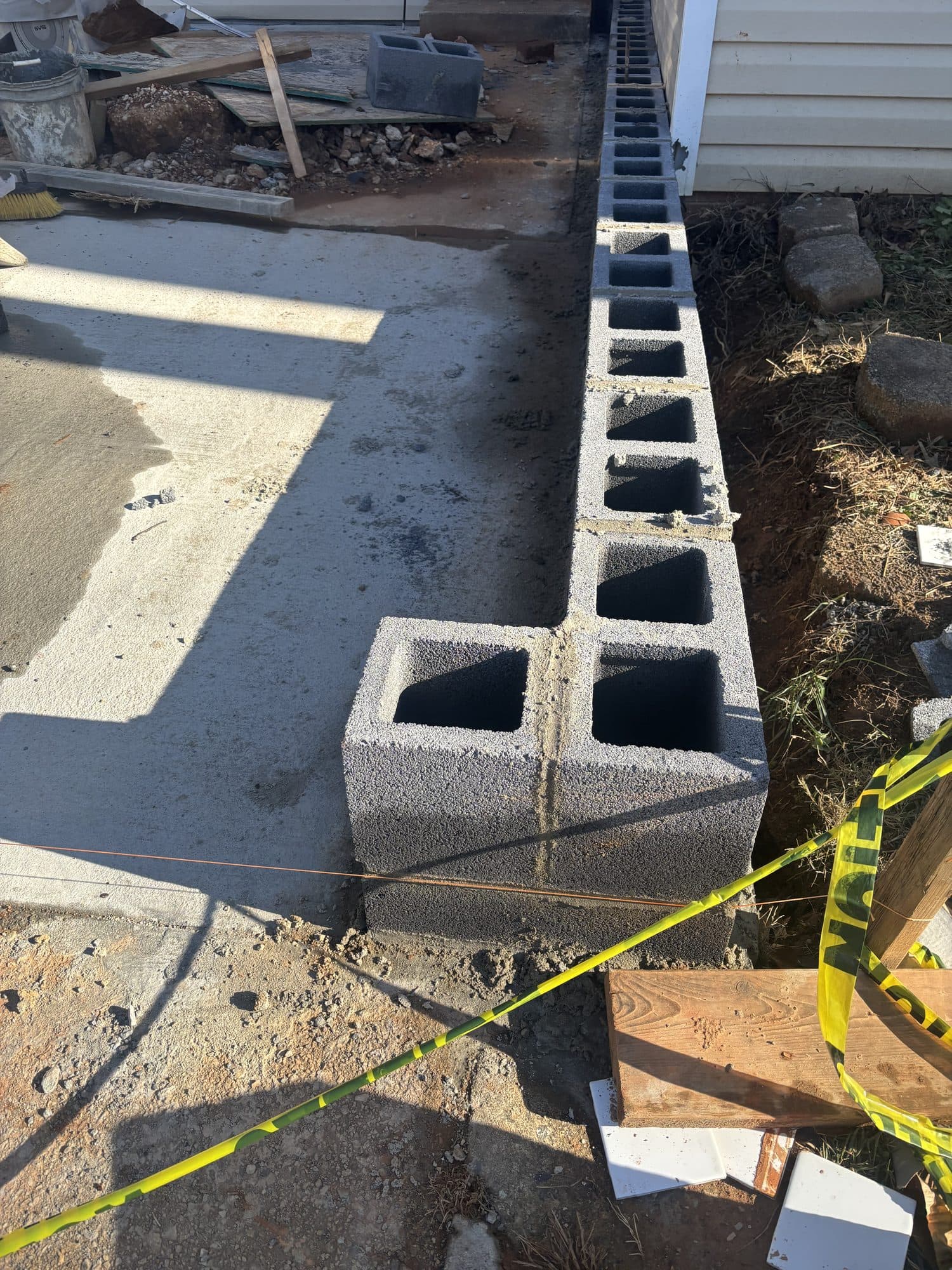 A single course of concrete masonry block laid along a footing edge beside a concrete slab. Foundation project by Potts Brothers Construction, Arlington & Northern Virginia