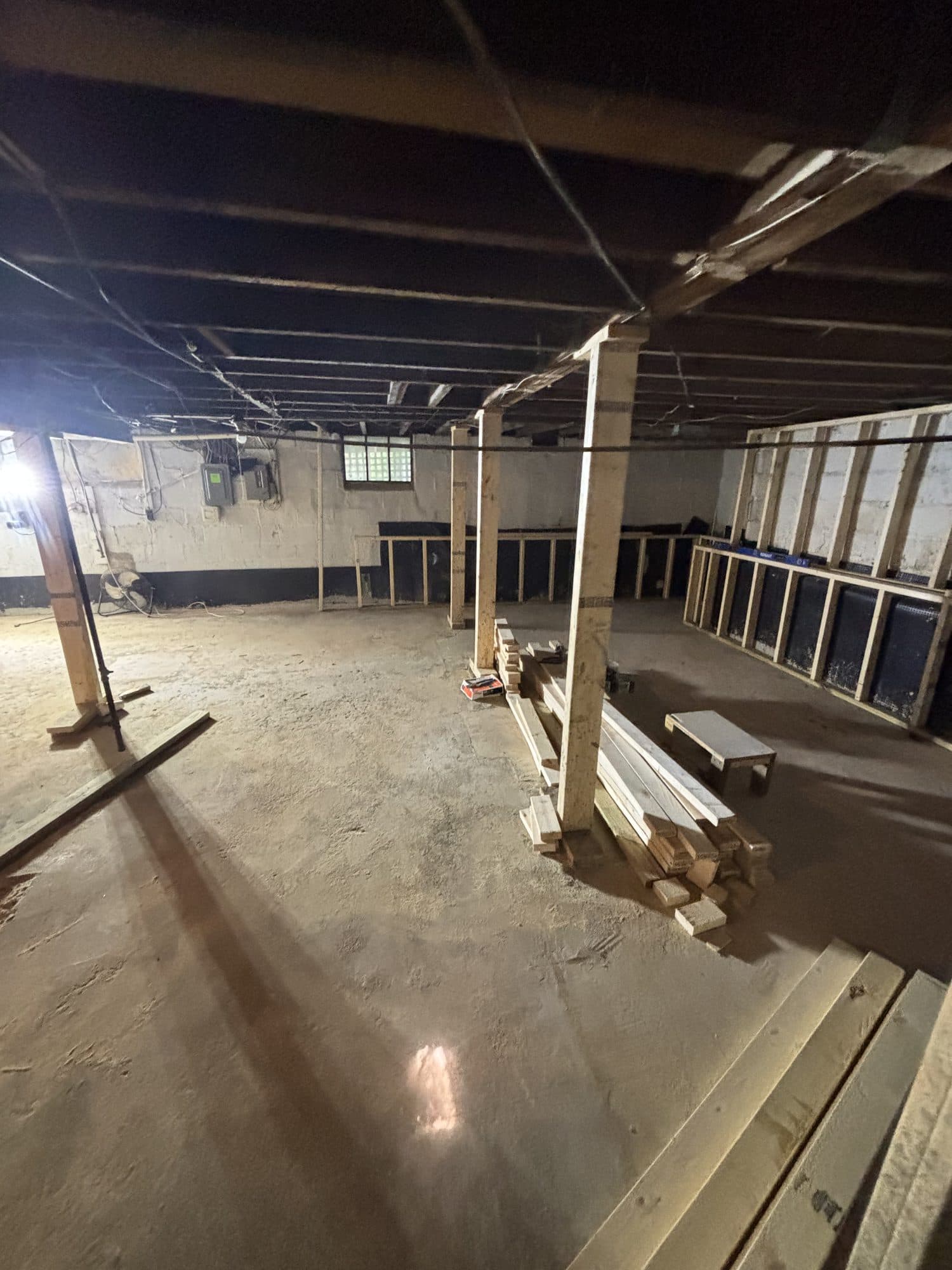 Wide basement interior with posts and lumber staged. Foundation project by Potts Brothers Construction, Arlington & Northern Virginia