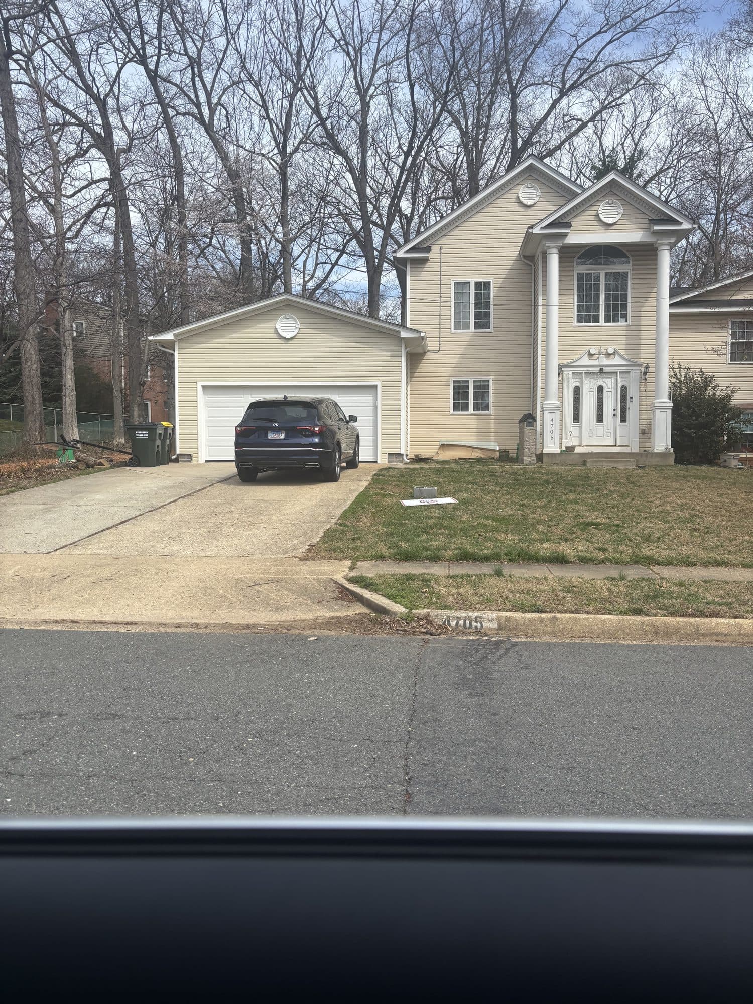 An attached single-car garage with a white overhead door on a finished tan two-story home. Garage project by Potts Brothers Construction, Arlington & Northern Virginia