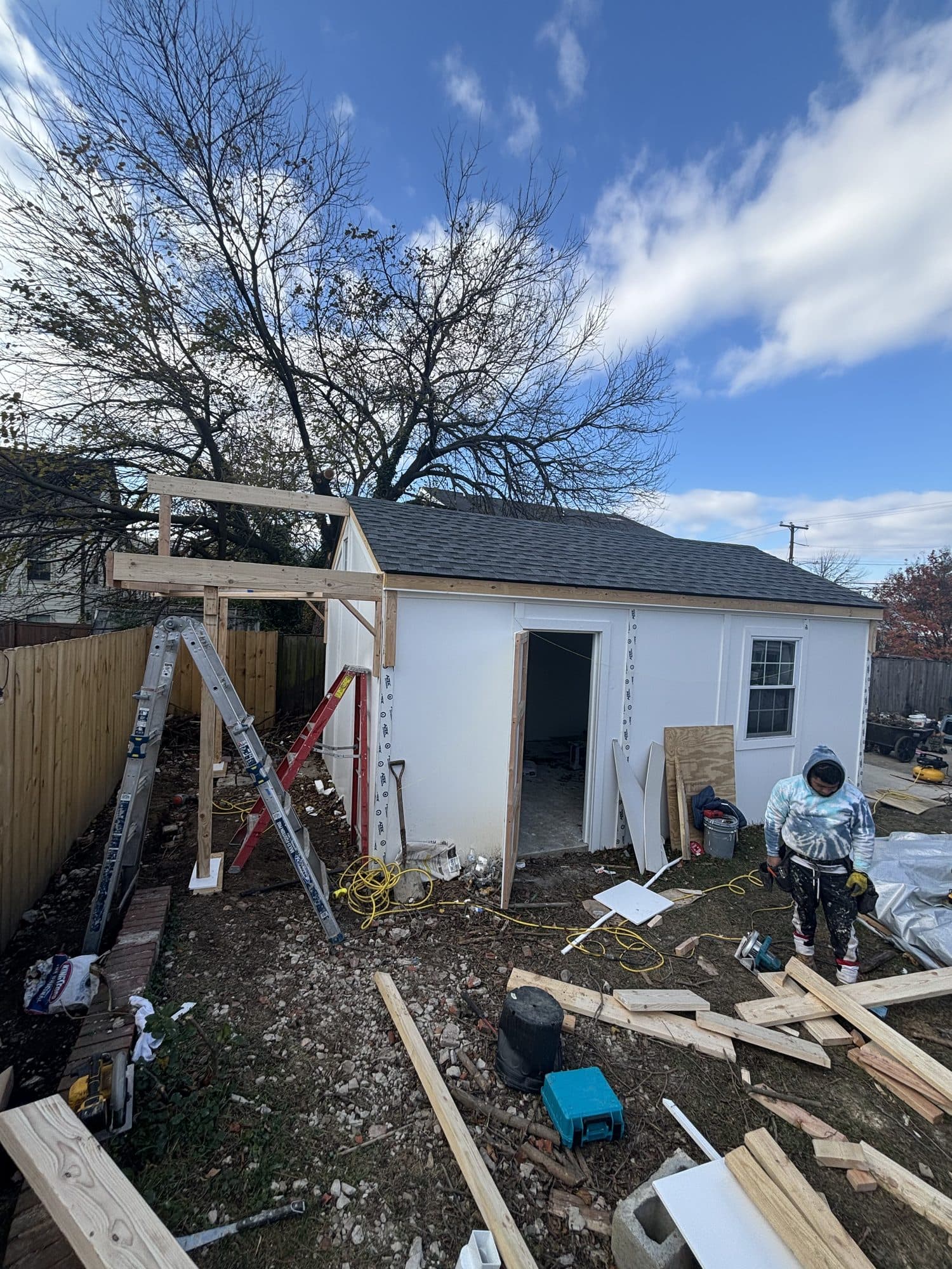 A detached garage-shed framed and partly sheathed in a fenced backyard, with a header beam set over the door opening. Garage project by Potts Brothers Construction, Arlington & Northern Virginia