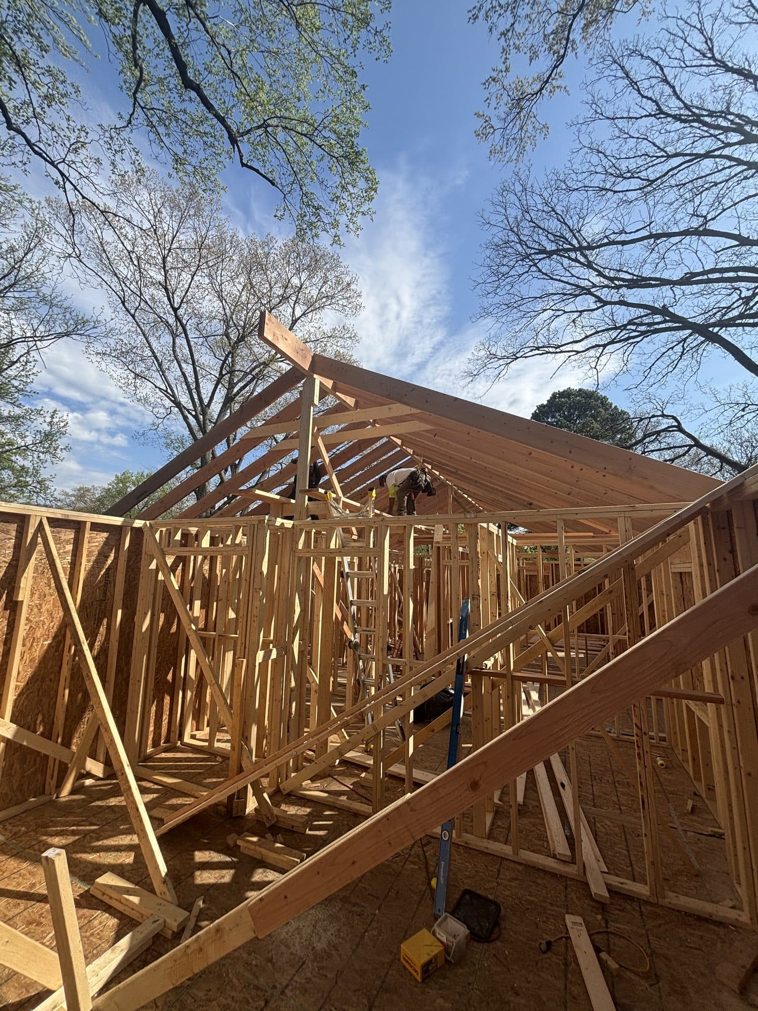 Detached garage under construction showing rafter and stud-wall framing against a blue sky with clouds. Garage project by Potts Brothers Construction, Arlington & Northern Virginia