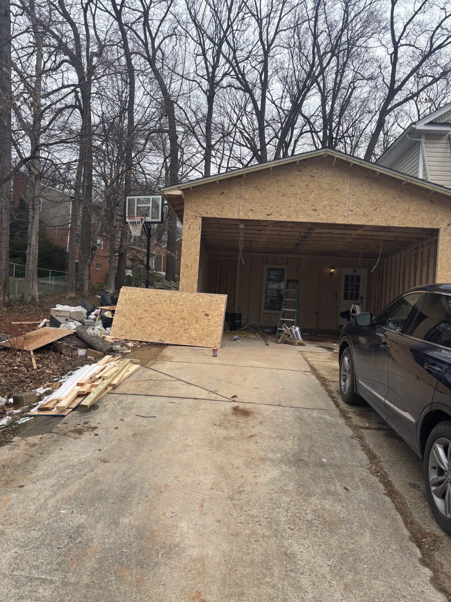 A detached two-car garage shell sheathed in OSB at the top of a driveway beside a finished home. Garage project by Potts Brothers Construction, Arlington & Northern Virginia