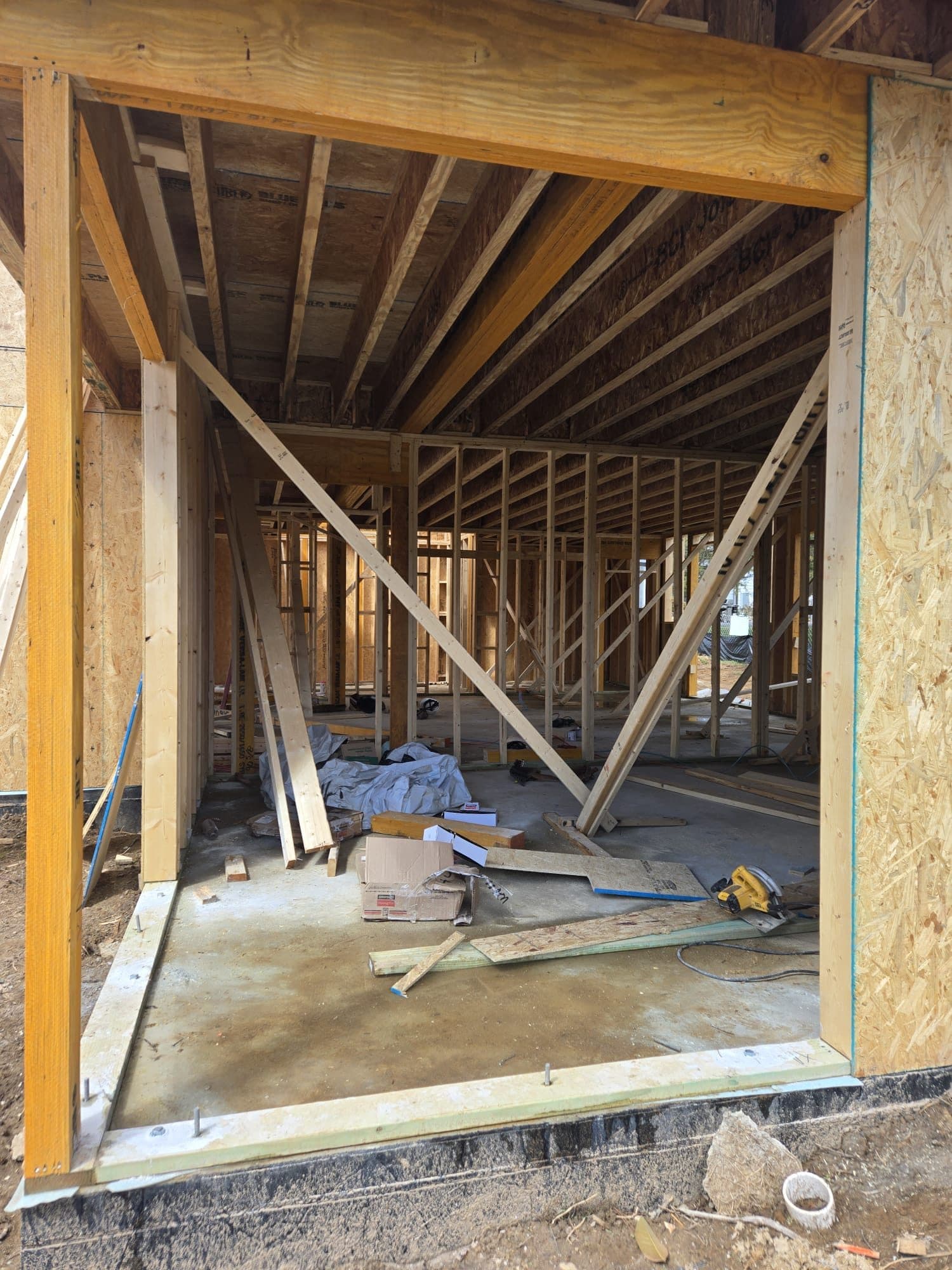 A framed garage bay opening with a header beam set over the concrete slab inside a stick-framed structure. Garage project by Potts Brothers Construction, Arlington & Northern Virginia