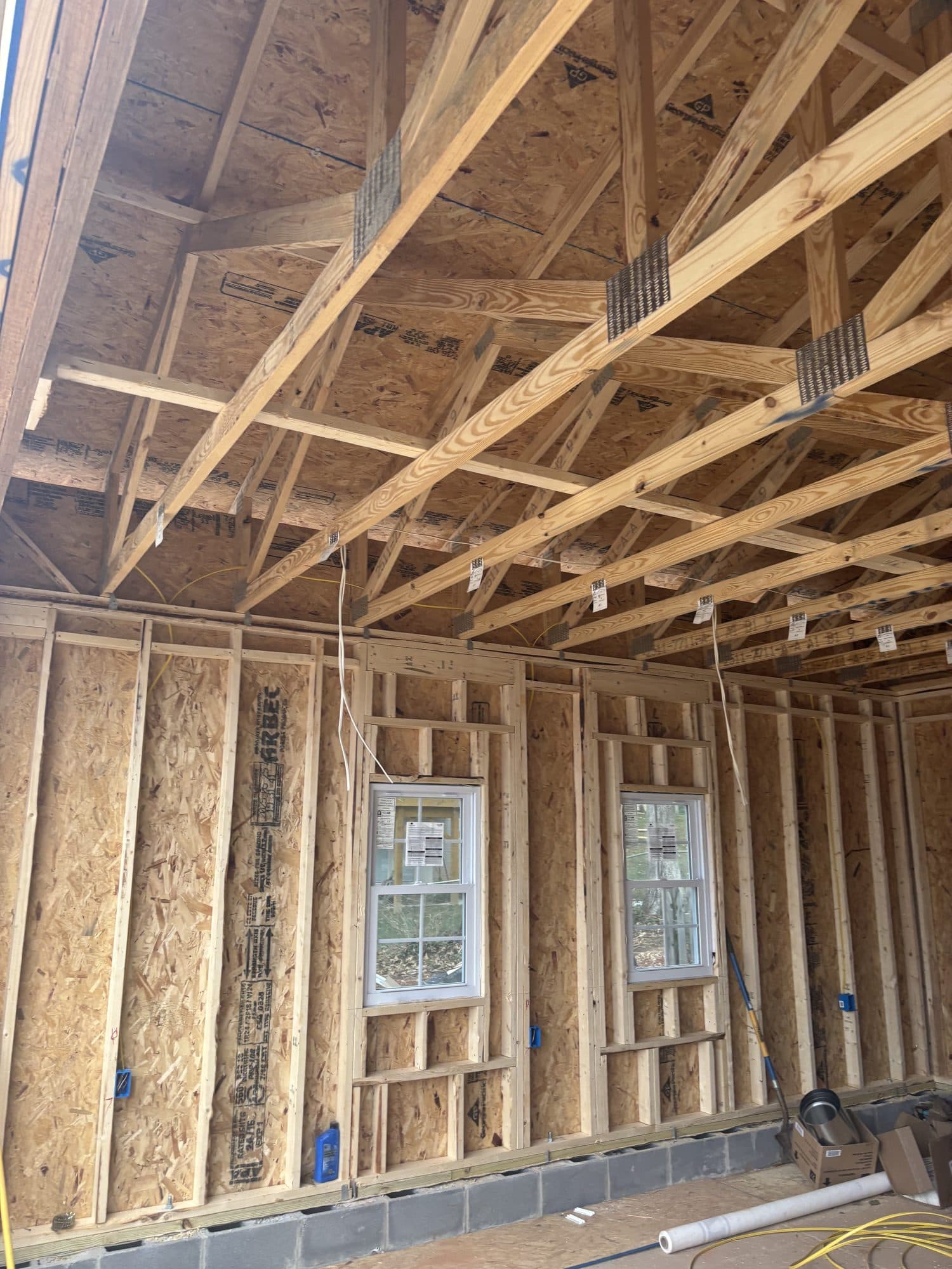 Inside a framed garage showing wood wall framing, two windows, exposed ceiling joists, and a block stem wall. Garage project by Potts Brothers Construction, Arlington & Northern Virginia