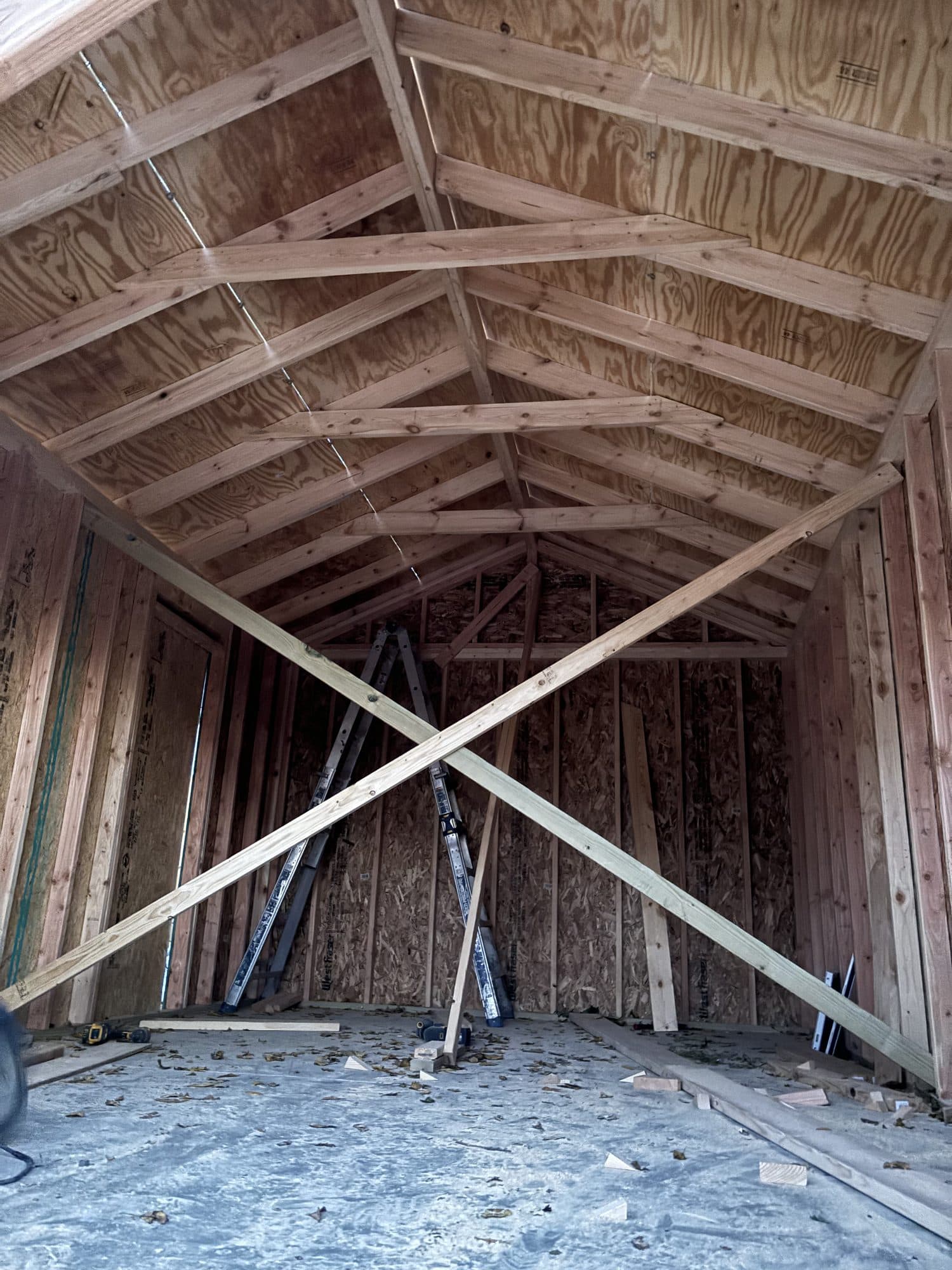 Interior view of a framed garage looking up at exposed rafters and trusses with diagonal bracing. Garage project by Potts Brothers Construction, Arlington & Northern Virginia