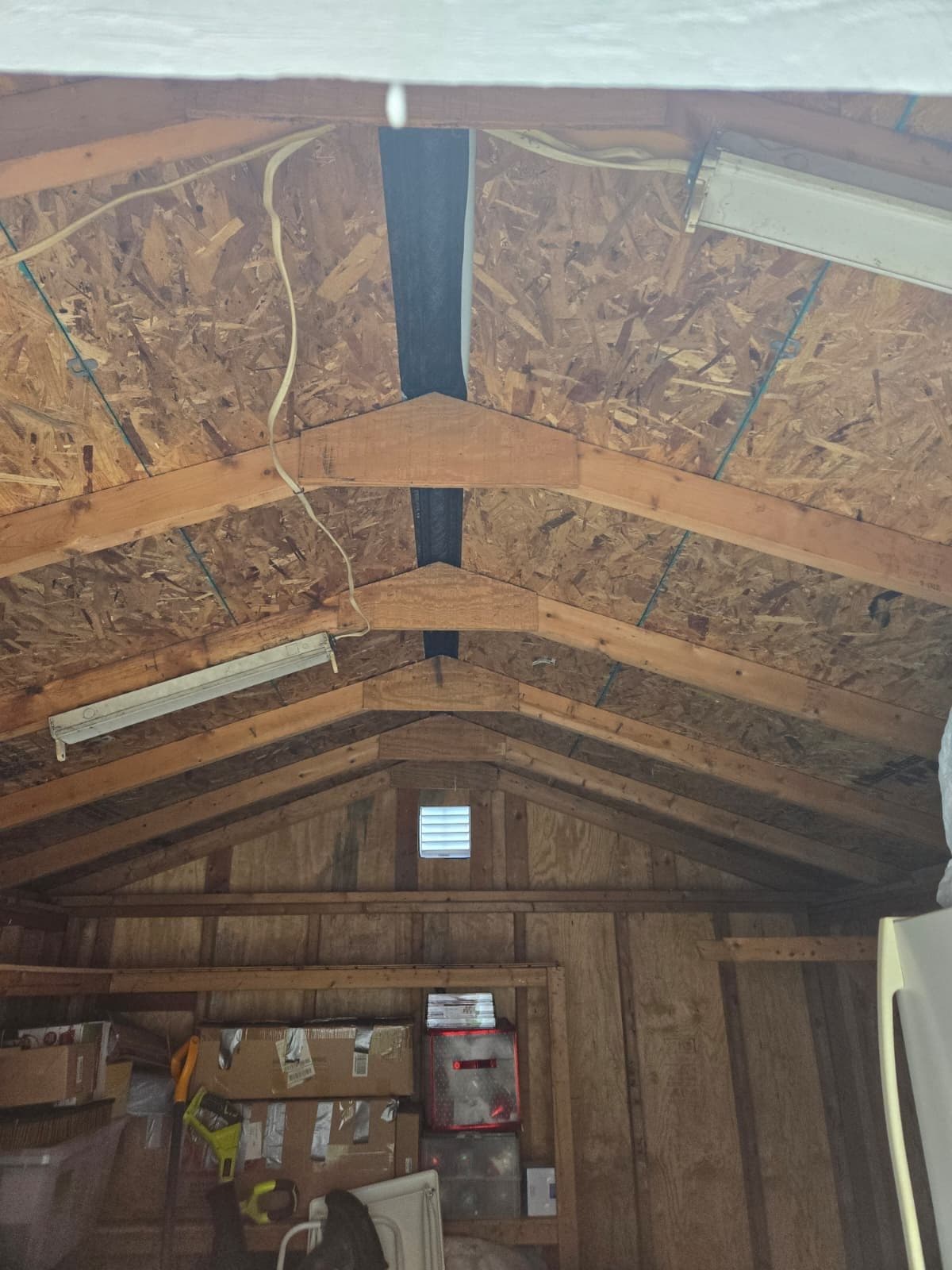 Interior of a shed garage showing OSB sheathing over wood rafters with a ridge vent and gable louver. Garage project by Potts Brothers Construction, Arlington & Northern Virginia