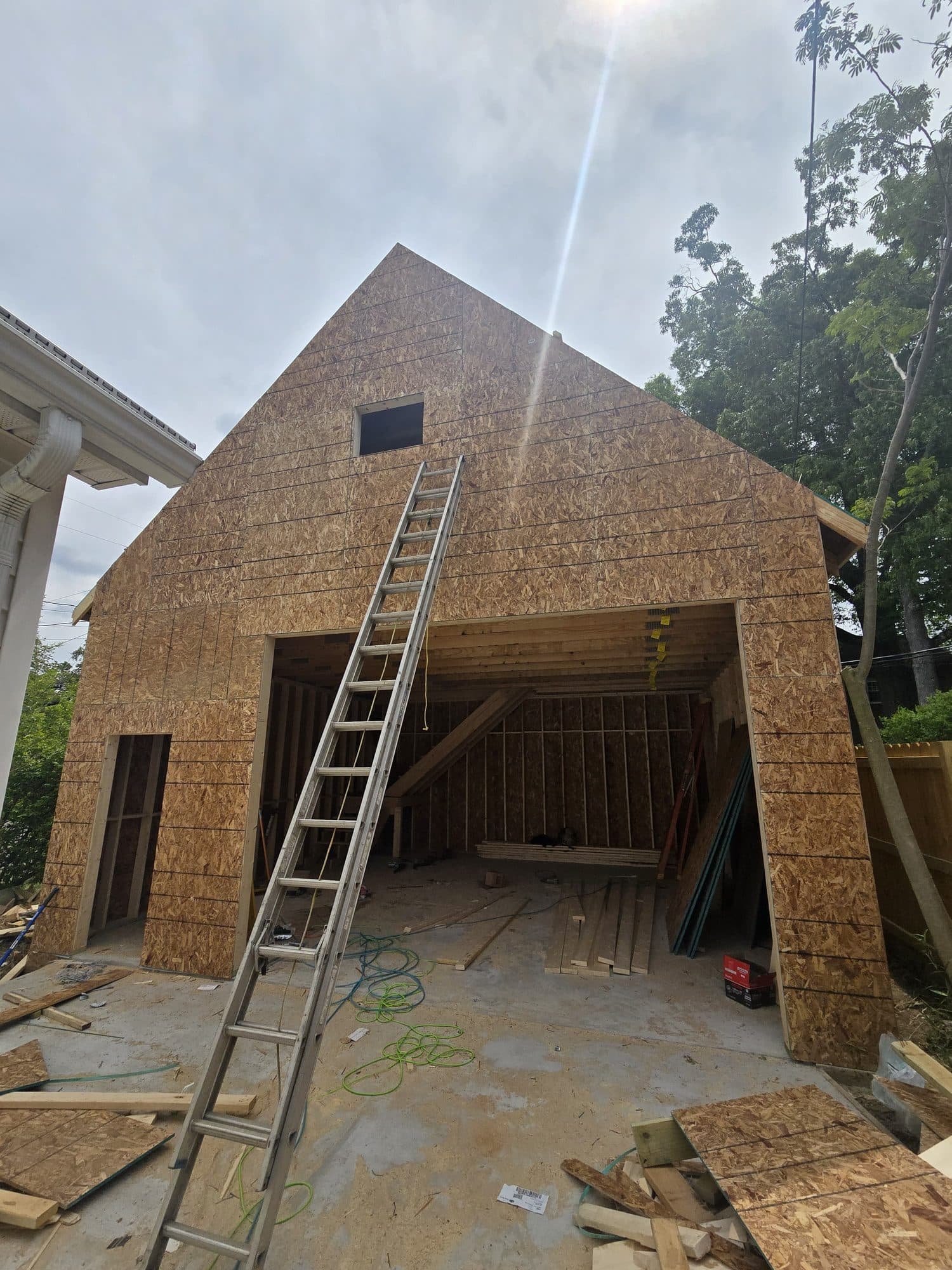 Detached two-story garage framed and sheathed in OSB with an open garage bay and ladder. Garage project by Potts Brothers Construction, Arlington & Northern Virginia