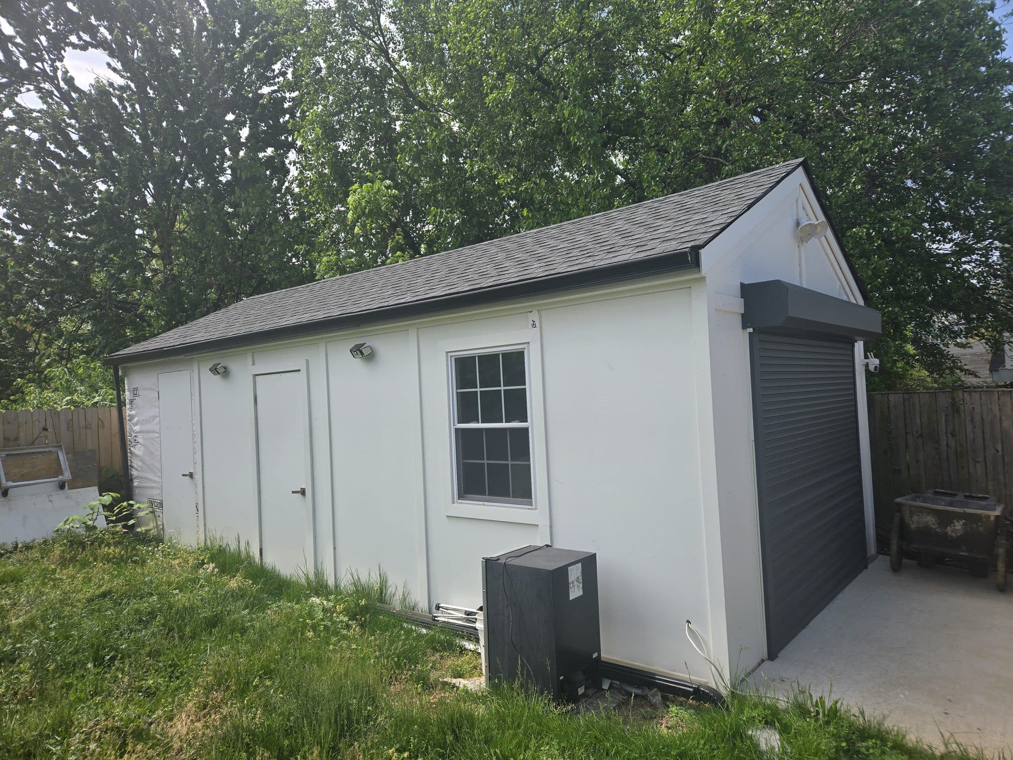 Detached white shed garage with roll-up door in backyard. Garage project by Potts Brothers Construction, Arlington & Northern Virginia