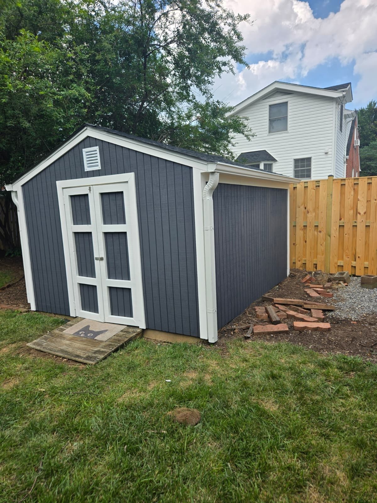 Finished detached garage shed with gray siding, white trim and double access doors in a fenced backyard. Garage project by Potts Brothers Construction, Arlington & Northern Virginia