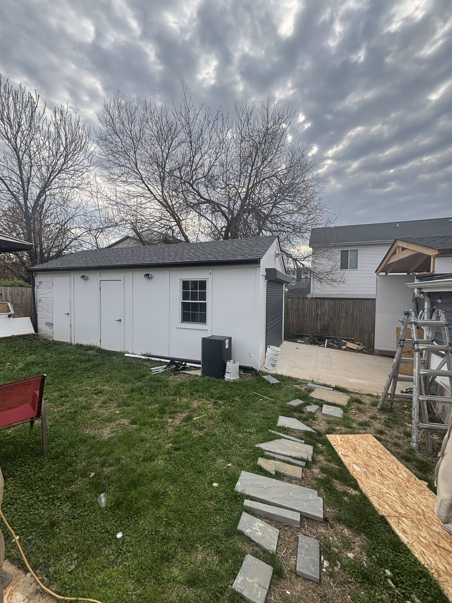 A finished white detached garage-shed in a backyard with a new flagstone walkway. Garage project by Potts Brothers Construction, Arlington & Northern Virginia